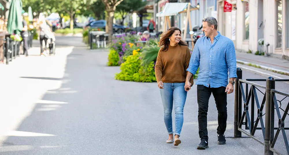 Man och kvinna håller handen och går längs med en promenadgata i Enköping.