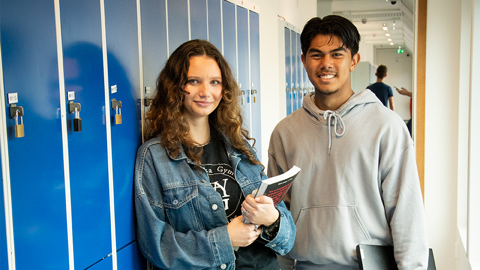 Foto på två elever som står i korridoren.